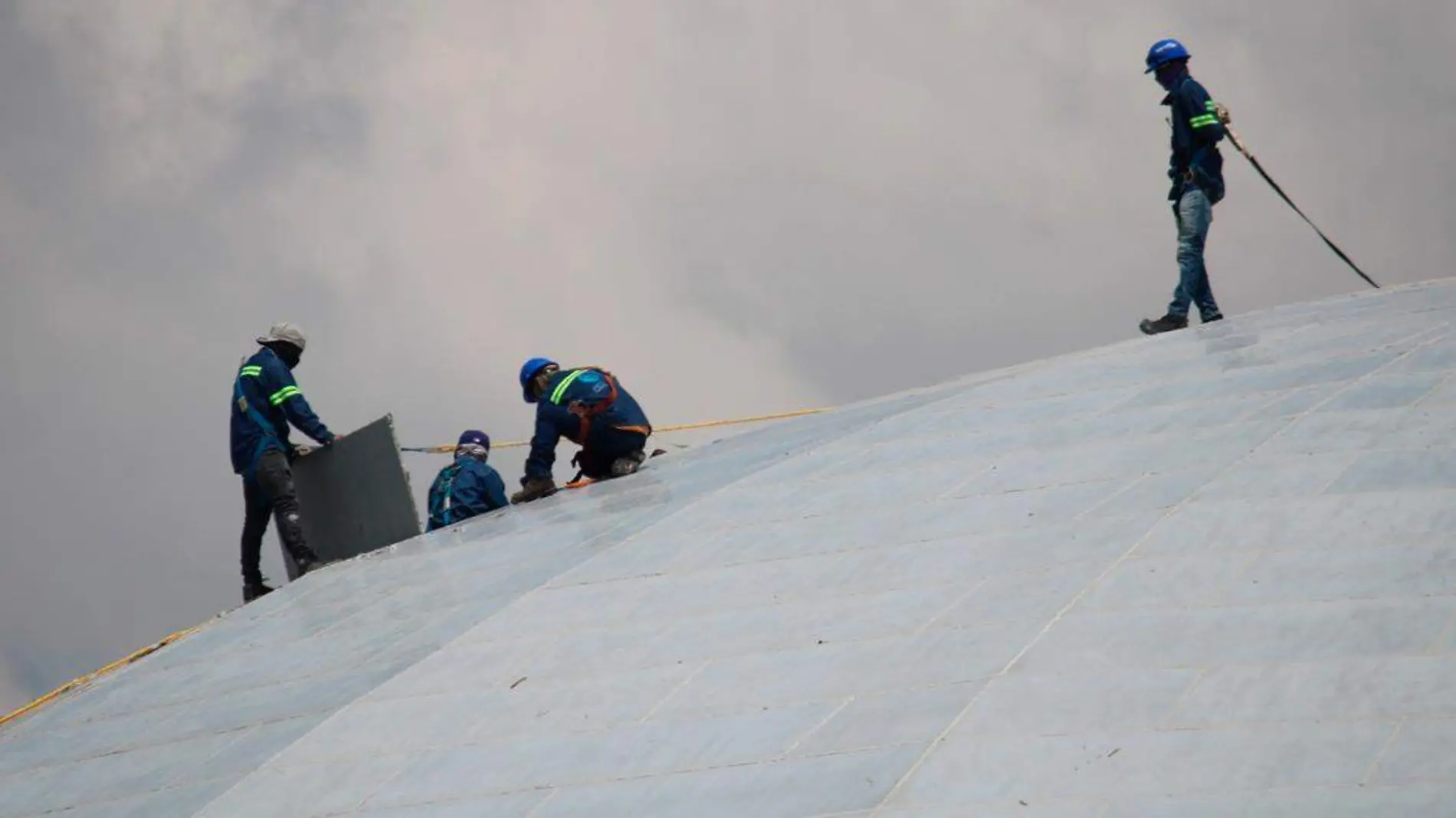 trabajadores realizando labores en la entrada principal y en el techo del auditorio